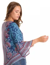 Blusa de gasa con estampado de arabescos y motivos florales en tonos azul marino, rojo y celeste. Presenta cuello redondo y mangas tres cuartos amplias. El bajo es asimétrico, más largo en los laterales.