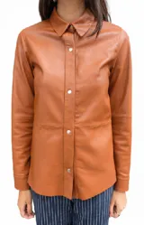 Camisa de cuero color suela, con cuello camisero, cierre frontal con broches metálicos y mangas largas con puños.