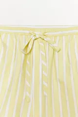 Bermuda corta tipo pijama con rayas verticales amarillas y blancas, tiro alto, cintura elástica ajustable con lazo y detalle de botones decorativos en el frente.
