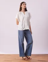 Blusa blanca texturada, marca Sabrina Lauren, con cuello a la base, escote en V con puntilla y lazo, mangas cortas amplias y aplique de puntilla.