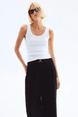 Pantalón sastre negro de punto crepé con pinzas, tiro alto, cintura elástica, cinturón decorativo con hebilla metálica y piernas amplias rectas.