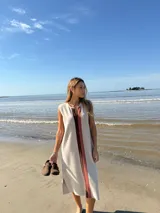 Vestido midi sin mangas color beige, con corte recto y detalle de franja vertical marrón en el centro.