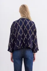 Kimono corto azul marino con estampado geométrico dorado, confeccionado en viscosa jacquard con lurex. Presenta guarda bordada en piedras y canutillos, y forrería interior.