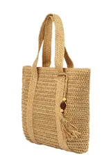Bolso de mano tipo tote de paja color beige, con asas de soga trenzada y detalle de borla con cuentas de madera.