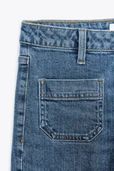 Pantalón de jean de tiro alto con bolsillos frontales y traseros. Corte recto y cierre frontal con cremallera y botón.