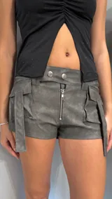 Short gris de tiro bajo confeccionado en vinilo, con cierre frontal y bolsillos laterales con solapa.