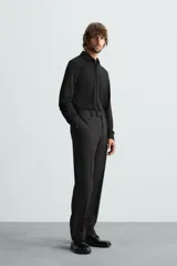 Camisa color beige de corte slim fit, confeccionada en tejido elástico que minimiza las arrugas. Tiene cuello italiano abierto, manga larga con puños abotonados y cierre frontal con botones.