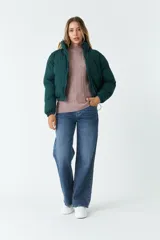Campera puffer verde oscuro de nylon, con cuello alto, cierre frontal con cremallera, bolsillos laterales y cintura ajustable con cordón.