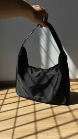 Cartera tipo baguette negra de lona semi impermeable con cierre metálico y forrería de gross con bolsillo interno.
