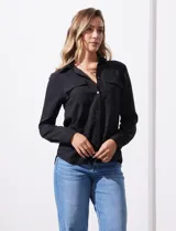 Camisa blanca de manga larga con cuello con solapa y abertura central con botones. Delantera con bolsillos aplicados.