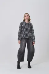 Chaqueta de manga larga con cuello a la base y cierre frontal. Presenta un estampado geométrico repetitivo en blanco y negro.