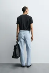 Pantalón de jean celeste de corte flare, con tiro medio, cinco bolsillos, cierre frontal con cremallera y botón, y bajo con acabado irregular.