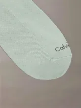 Pack de tres pares de medias invisibles Calvin Klein, en color blanco, gris y verde. Cada media tiene el logo 'ck' en el tobillo y el nombre 'Calvin Klein' en la planta del pie.