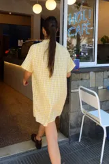 Vestido corto camisero a cuadros celestes y blancos, de corte amplio y cuello mao. Tiene botones a tono y logo bordado en el frente.