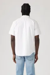 Camisa blanca a rayas verticales finas, de manga corta, con cuello clásico, cierre frontal con botones y un bolsillo en el pecho.