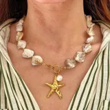 Collar con cuentas de nácar irregulares, cadena dorada y dije colgante de estrella de mar dorada con una perla.