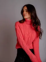 Sweater de punto trenzado color coral, con cuello alto y mangas largas.