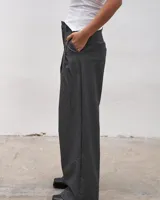 Pantalón sastrero de corte amplio en tono gris, con diseño de pinzas y bolsillos laterales.