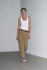 Pantalón cropped color beige de tiro alto y corte recto, confeccionado en algodón. Cuenta con bolsillos delanteros y traseros, trabillas en la cintura y cierre frontal con cremallera y botón.