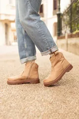 Bota de cuero color marrón claro, con caña baja, suela track y cierre lateral con cremallera.