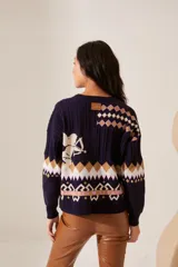 Cardigan azul marino de punto con cuello redondo y cierre frontal con botones. Presenta diseño con motivos geométricos en tonos beige, blanco y rosa, y un dibujo de un cupido en el pecho.