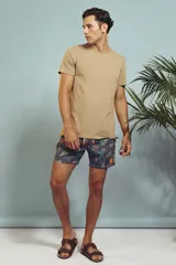 Short de baño con estampado de hojas en tonos grises y celestes, con cordón ajustable en la cintura y detalle de franja lateral con rayas rojas, blancas y negras.