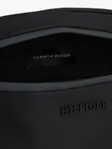 Riñonera negra Tommy Hilfiger con logo texturizado en el frente y cinta distintiva en el lateral. Cuenta con cierre de cremallera, correa ajustable de textil trenzado y bolsillo interior con cremallera.
