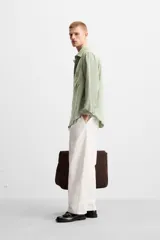 Camisa verde claro de corte relaxed fit confeccionada en tejido con mezcla de modal. Tiene cuello italiano, manga larga con puños abotonados, bolsillo de parche en el pecho y cierre frontal abotonado.
