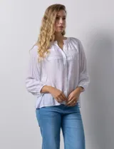 Blusa blanca de gasa bambula con cuello a la base y apertura central con botones. Apliques de crochet en la parte delantera y en las mangas ¾ con terminación fruncida.
