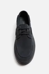 Zapato náutico de cuero color azul marino con cordones finos y suela plana.