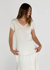 Remera beige de manga corta con escote en V y detalle de encaje en el escote y las mangas.