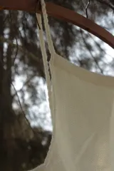 Top tejido color crudo, de algodón, con breteles finos y corte recto.