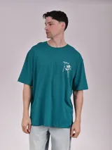Remera verde con estampado de texto y dibujo de una flor en el frente.