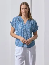 Blusa celeste estampada con motivos de playa, con cuello a la base y escote en V. Mangas cortas con detalle fruncido.