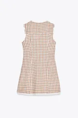 Vestido corto de escote pico con cuello bobo y manga sisa. Detalle de flores bordadas y entredoses. Forro interior. Cierre frontal con botones forrados y lazada. Estampado a cuadros vichy color marrón y blanco.