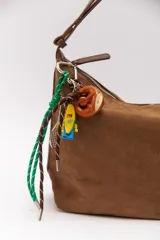 Llavero con forma de pretzel marrón, con cordones verde y marrón, un muñeco de lego con forma de banana y una raqueta de tenis en miniatura.