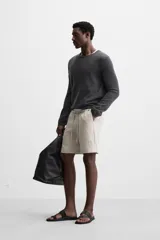 Bermuda regular fit negra confeccionada en tejido de lino. Cintura elástica ajustable con cordón y pliegues frontales. Bolsillos frontales y detalle de bolsillos traseros de plastrón.