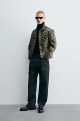 Cazadora corta (cropped fit) de piel con acabado de pelo, estampado abstracto en tonos negro y beige/tostado. Presenta cuello solapa, manga larga y cierre frontal con botones metálicos.