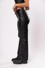 Pantalón de tiro alto negro de gabardina strech metalizada, con bolsillos y cierre frontal con cremallera y botón.