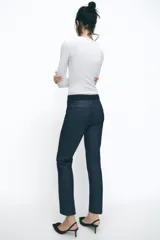Pantalón tobillero azul oscuro, de tiro medio con cintura elástica en la espalda. Tiene bolsillos delanteros y falsos bolsillos de vivo en la parte trasera. El bajo está acabado con aberturas laterales.