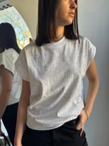 Remera blanca de algodón con cuello redondo y mangas cortas con strass plateado formando líneas verticales.
