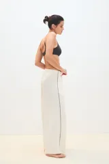 Pantalón palazzo color crudo con una fina línea negra en los laterales.