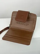 Billetera pequeña de cuero marrón con aplique de cuero vacuno blanco y negro. Cierre con cremallera y correa de muñeca.
