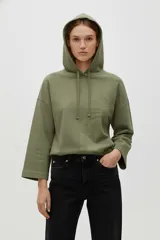 Buzo con capucha color verde oliva, de manga larga y corte holgado. Presenta un diseño sutil de palmera bordado en tono similar en el frente.