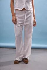 Pantalón blanco de corte amplio con cintura elastizada y cordón ajustable.