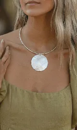 Gargantilla rígida plateada con dije circular de nácar.