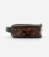 Neceser rectangular grande de plástico transparente con estampado de carey en tonos marrones. Tiene cierre de cremallera doble dorada, asa de mano negra y ribete negro.