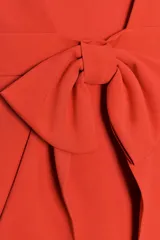 Vestido corto color rojo, confeccionado en tejido elástico, con escote recto y tirantes finos. Presenta detalle de lazo en la espalda y cierre lateral con cremallera oculta.