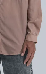 Camisa manga larga rosa con bolsillo con ojal y botón en delantero, de calce oversize confeccionada en textil plano fresco y liviano.