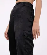 Pantalón jogger negro de poliéster con rayas laterales y cadena decorativa.